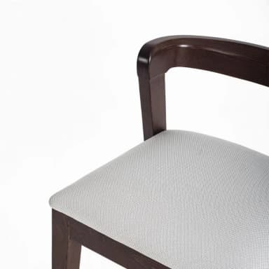 A close-up view of a chair, focusing on the armrest, back support, and seat. The chair features a dark wood frame with a curved, integrated armrest. The seat is upholstered in a light-colored fabric with a subtle woven texture. — 3D model
