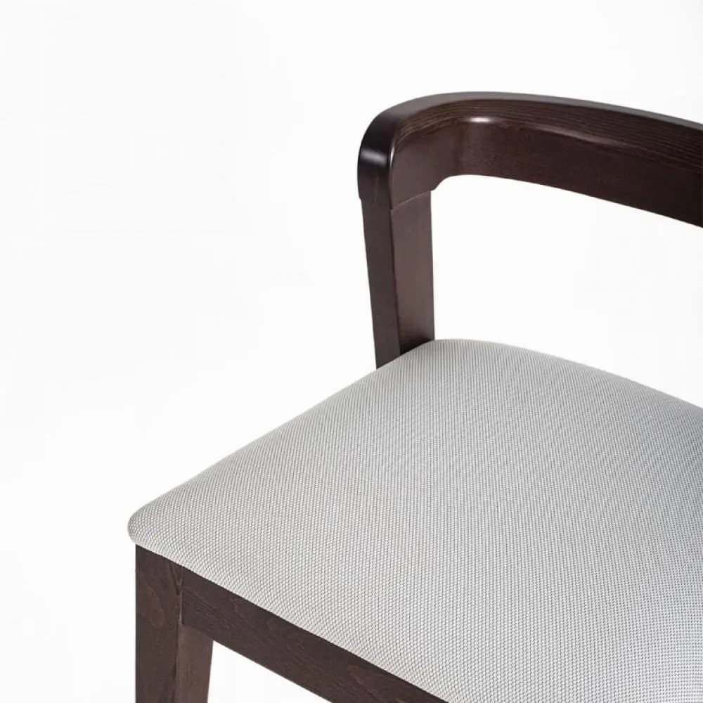 A close-up view of a chair, focusing on the armrest, back support, and seat. The chair features a dark wood frame with a curved, integrated armrest. The seat is upholstered in a light-colored fabric with a subtle woven texture. — 3D model