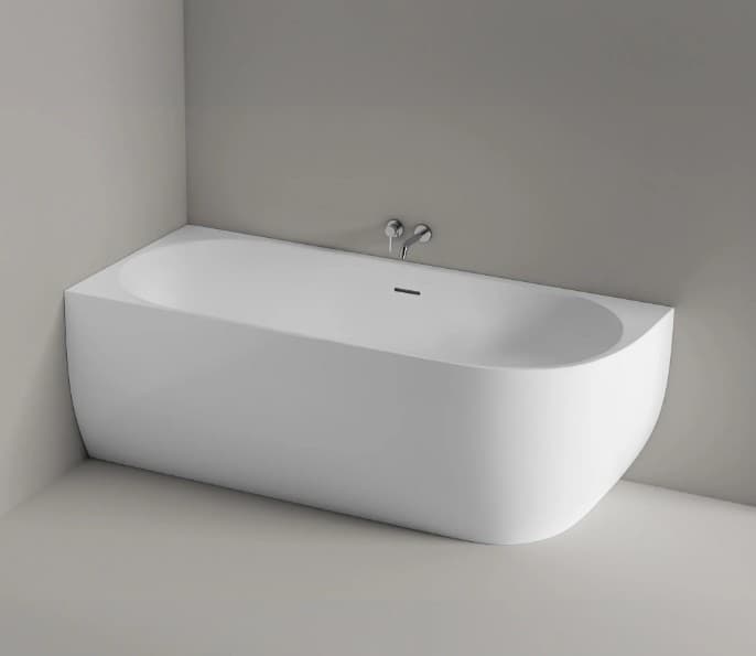 A modern, freestanding bathtub designed for corner installation. It features a smooth, curved exterior and a minimalist aesthetic. The tub is white and appears to be made of a solid surface material. Chrome faucets are mounted on the wall above the tub, and a linear drain is visible within the basin. — 3D model