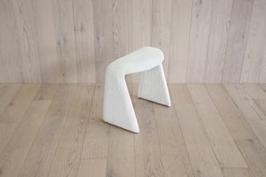 A white, textured stool with a unique U-shaped base. The stool appears to be upholstered in a boucle or teddy bear fabric. Its curved structure provides a modern and organic aesthetic. — 3D model