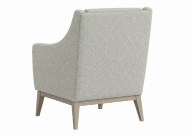 A upholstered armchair viewed from the rear. The chair features a high back with a slightly curved top edge and integrated armrests. The upholstery is a light grey fabric with a diamond-patterned weave in a lighter contrasting thread. The chair is supported by a wooden base and four tapered legs, appearing to be made of light-colored wood. — 3D model
