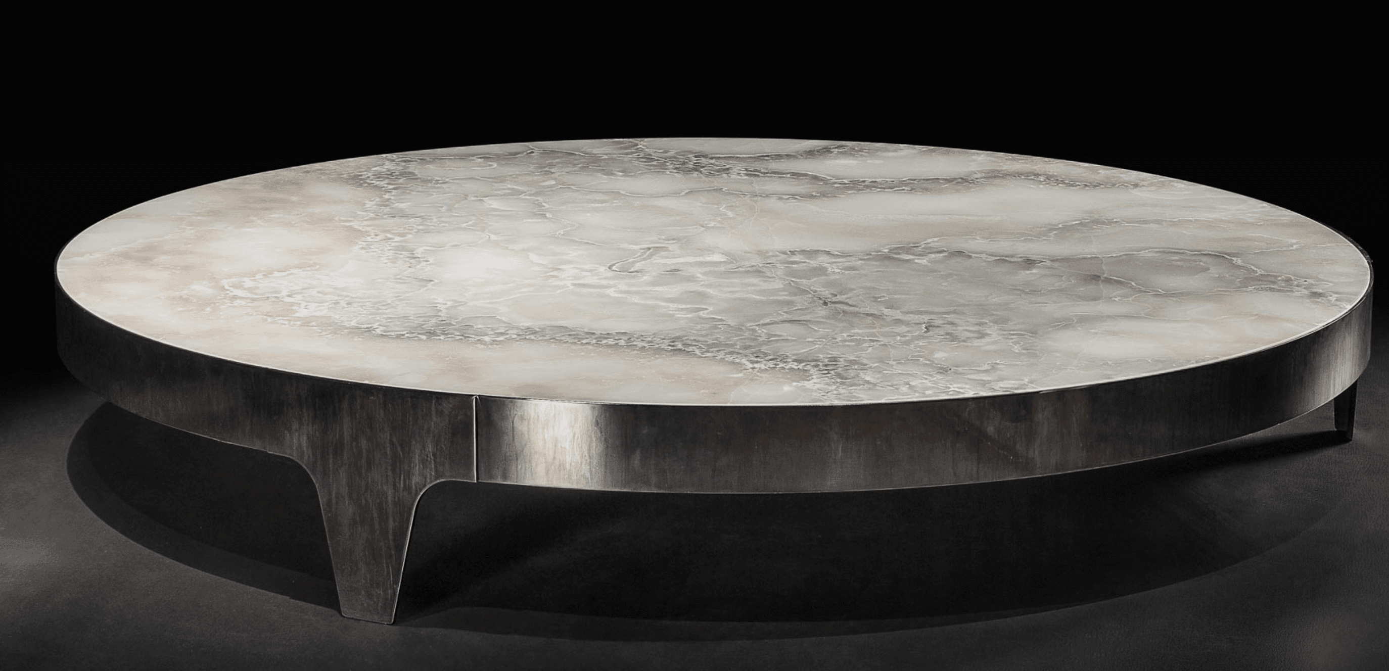 A round coffee table featuring a polished onyx tabletop with natural variegated patterns in white, beige, and grey tones, set upon a robust, patinated dark metal base with integrated, tapered legs. — 3D model