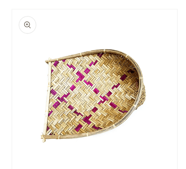 A traditional handwoven bamboo winnowing basket, characterized by its shallow, scoop-like form with a flat base and raised, curved edges. The weave features a distinct herringbone pattern created by alternating lighter and slightly darker bamboo strips, suggesting different natural shades or processing. The rim is reinforced with thicker bamboo strips, and the corners or handles are secured with wrapped twine. — 3D model