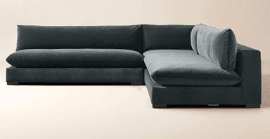 A deep-seated, modular sectional sofa with a low profile and plush cushioning. The sofa features a dark gray, velvet-like upholstery and a clean-lined, contemporary design. It is configured in an L-shape, suggesting a chaise lounge component on the right side. — 3D model