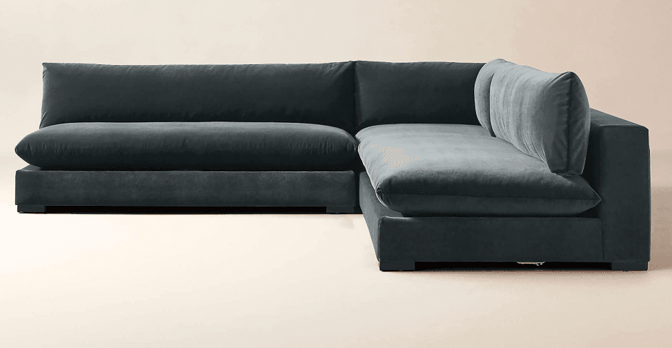 A deep-seated, modular sectional sofa with a low profile and plush cushioning. The sofa features a dark gray, velvet-like upholstery and a clean-lined, contemporary design. It is configured in an L-shape, suggesting a chaise lounge component on the right side. — 3D model
