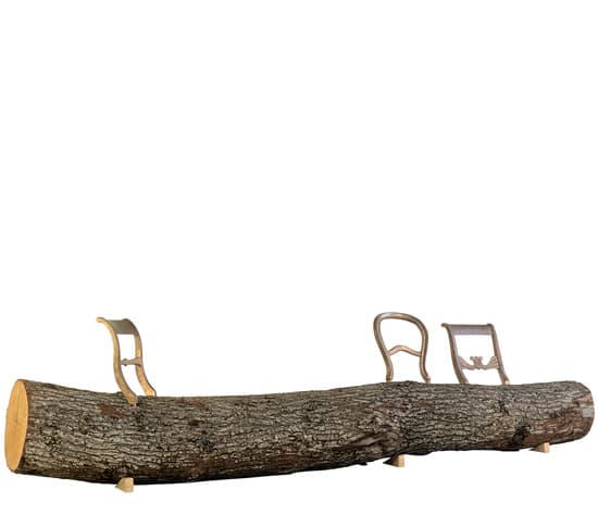 A long, raw, unrefined tree log functions as the main seating surface, supported by smaller wooden blocks underneath. Attached to the top of the log are three distinct, ornately carved wooden chair backrests. Each backrest features a traditional, somewhat baroque or rococo-inspired design with decorative flourishes. The log itself has visible bark texture and a natural brown color, while the backrests appear to be made of a lighter-colored wood, possibly painted or stained, complementing the rustic aesthetic with an unexpected touch of classical elegance. The overall piece is a functional yet highly artistic bench. — 3D model