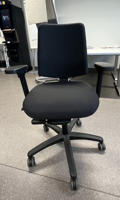 A modern office chair featuring black fabric upholstery on both the seat and backrest. It has a five-star swivel base made of black plastic, equipped with caster wheels for mobility. The chair includes black plastic armrests that appear to be adjustable. The design is functional and contemporary, suitable for various office or home workspace environments. — 3D model