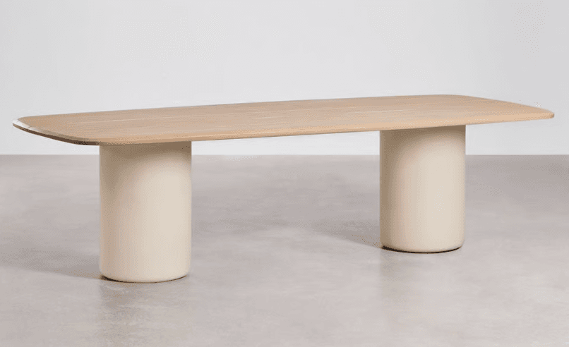A contemporary dining table featuring a rectangular light-toned wooden top with gently rounded corners. It is supported by two large, solid, cylindrical pedestal bases finished in a smooth, matte, cream or beige color, creating a minimalist and sculptural aesthetic. — 3D model
