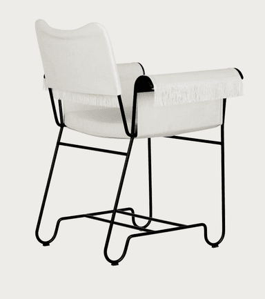 A contemporary armchair featuring a minimalist black metal tubular frame and upholstered seat, back, and armrests. The upholstery is off-white or cream-colored fabric, and the armrests are adorned with a distinctive fringe detail. — 3D model
