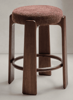 A wooden stool with a round, upholstered seat. The stool has four legs that are carved from wood and are joined by a circular wooden footrest. The seat is covered in a textured, woven fabric with visible threads of red and white. — 3D model