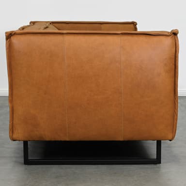 A contemporary three-seater sofa featuring tan-colored, possibly distressed leather upholstery and a minimalist black metal sled base. The sofa has wide, squared-off armrests and back, with visible piping and stitching details defining the cushions and edges. The overall aesthetic is modern and streamlined. — 3D model