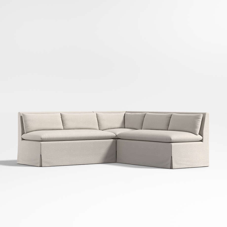 A sectional sofa with a skirted base and loose back cushions. The sofa is upholstered in a light-colored fabric and features a neutral, contemporary design. — 3D model