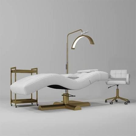 A modern white upholstered salon treatment chair featuring a contoured, reclining form and a gold-finished pedestal swivel base. It is accompanied by an integrated gold-finished floor lamp with an LED ring light, designed for professional beauty and aesthetic services. — 3D model