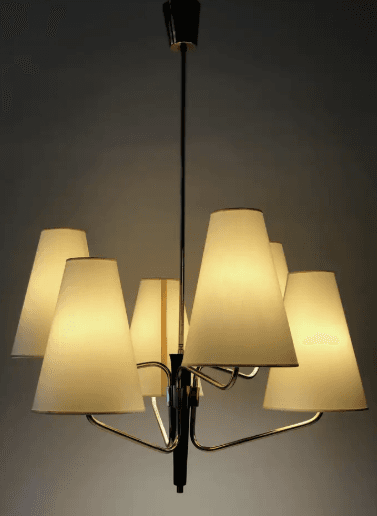 A vintage Mid-Century Modern chandelier featuring a central brass stem descending from a ceiling canopy. Six radiating arms, also in brass, extend outwards, each terminating in an upward-pointing, conical, off-white fabric shade. The central column has a prominent black accent piece, providing a striking contrast to the brass finish. The design is characteristic of the 1950s to 1960s, emphasizing clean lines and functional elegance. — 3D model