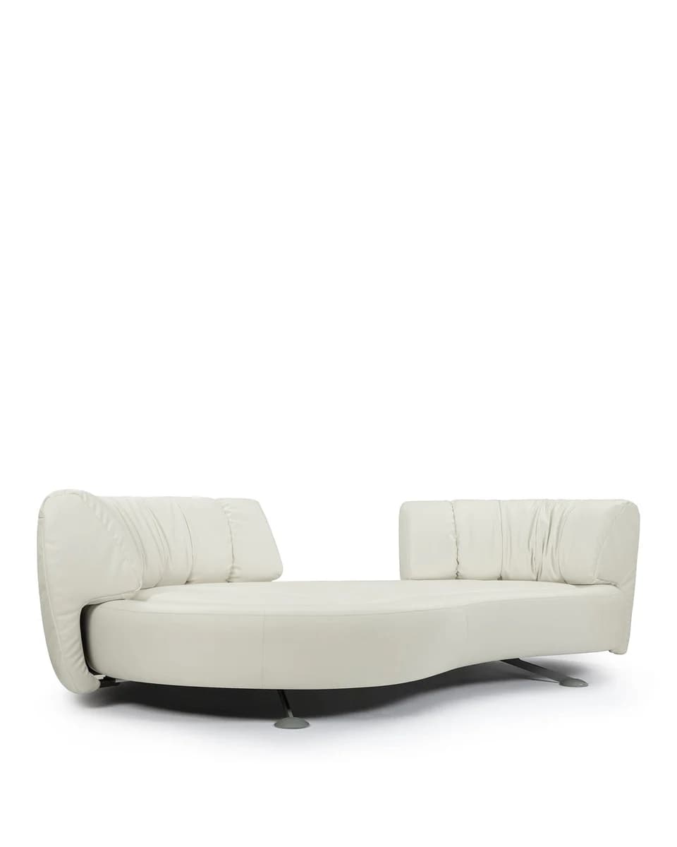 A contemporary, low-profile sofa with a curved, organic form. It features a generously padded seat and backrest with a tufted or gathered effect on the upper sections of the backrests. The sofa has a unique wavy silhouette, with integrated armrests or headrests at each end that follow the overall design. It is supported by slender, minimalist metal legs. — 3D model