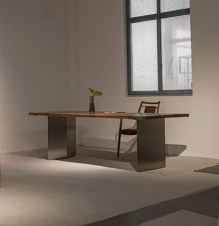 A contemporary dining table featuring a live-edge wooden tabletop and two solid, rectangular metal bases. The tabletop exhibits natural, irregular edges and a prominent wood grain, suggesting a single slab or carefully joined pieces. The bases are dark, matte grey, providing sturdy support and a modern contrast to the organic top. — 3D model