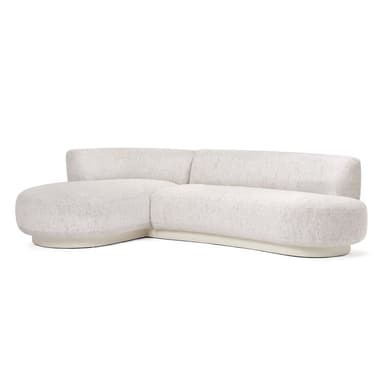 A contemporary modular sectional sofa, upholstered in a light, textured fabric, featuring a curved silhouette and an integrated chaise lounge. The sofa has a low, rounded profile with plush backrests and seats, resting on a recessed plinth base. — 3D model