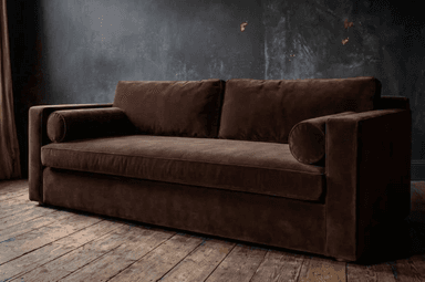 A modern, upholstered sofa with a rich brown fabric. It features a clean, rectangular silhouette with slightly rounded edges on the arms and back cushions. Two square back cushions and two cylindrical bolster pillows are visible. The sofa has a low profile and a single, continuous seat cushion. — 3D model