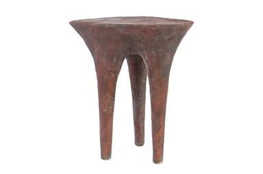 A small, three-legged end table with a textured, organic form. The tabletop is roughly circular and tapers downwards into three bulbous legs that spread outwards. The surface texture appears rough and pitted, suggesting a material like concrete, plaster, or a textured resin. — 3D model