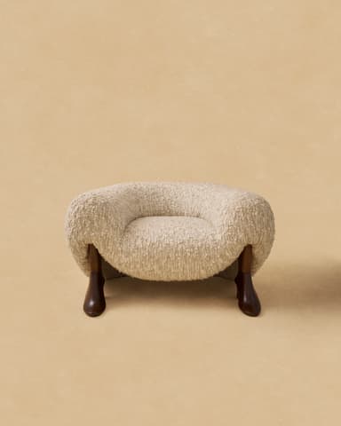 A light beige, rectangular ottoman with rounded edges, upholstered in a textured boucle fabric, appearing soft and minimalist against a plain tan background. — 3D model