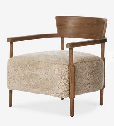 A contemporary armchair featuring a light brown wooden frame and a plush, light beige boucle or sherpa upholstered seat and backrest. The frame includes integrated armrests and subtly shaped legs. The backrest is a curved wooden panel. — 3D model