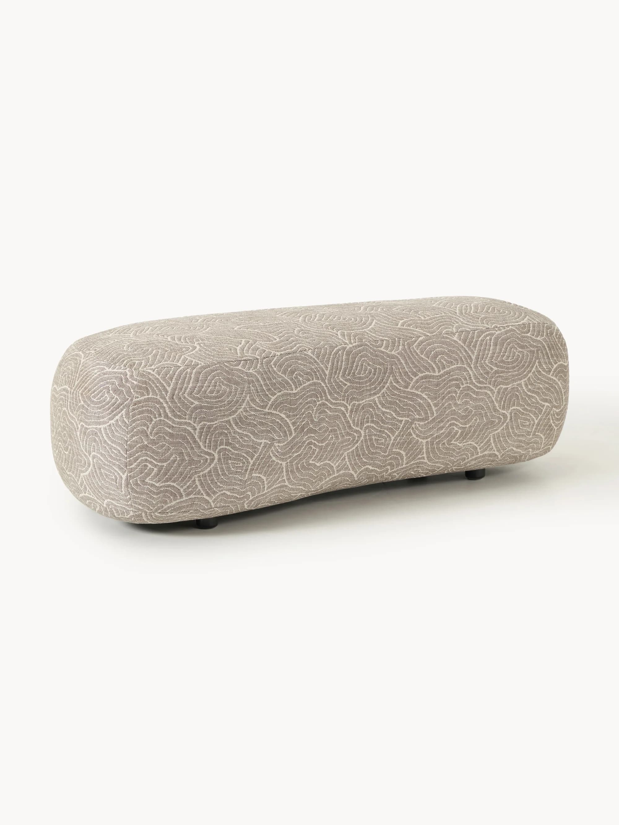 An oblong-shaped ottoman with rounded edges, upholstered in a fabric featuring a repeating organic, wave-like pattern in a neutral color palette of beige and off-white. It rests on small, dark legs. — 3D model