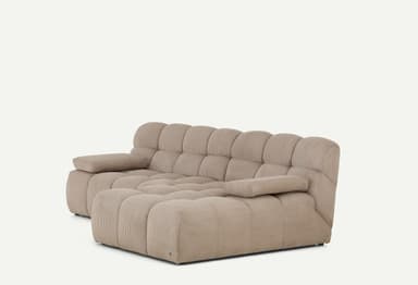 A light beige, modular sectional sofa featuring a chaise lounge component on the right side. The entire sofa is upholstered in a ribbed corduroy fabric, giving it a plush, textured appearance. It consists of deep, blocky cushions for both the seat and backrest, arranged in a low-profile, contemporary style. The armrests are similarly upholstered and integrated, providing a soft, rounded look. — 3D model