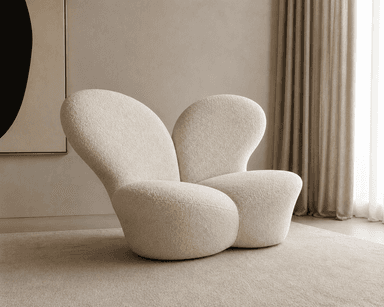 A sculptural, low-profile lounge chair upholstered in cream-colored bouclé fabric. The chair features a distinct organic form with smooth, continuous curves forming the seat, back, and integrated armrests. Its plush appearance suggests comfort, and the overall design is contemporary and minimalist, resting directly on the floor without visible legs. — 3D model