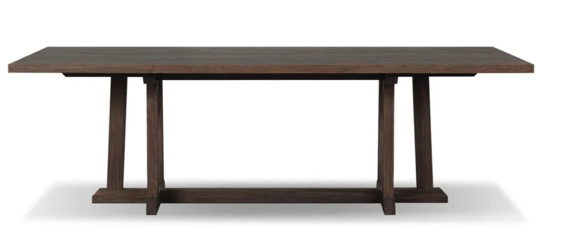 A contemporary dining table featuring a rectangular dark wood tabletop supported by a robust trestle base. The base consists of two vertical supports on each side, connected by a lower horizontal stretcher, creating a sturdy and visually substantial foundation. The wood has a deep, rich brown finish, highlighting its natural grain and presenting a solid, enduring aesthetic. — 3D model