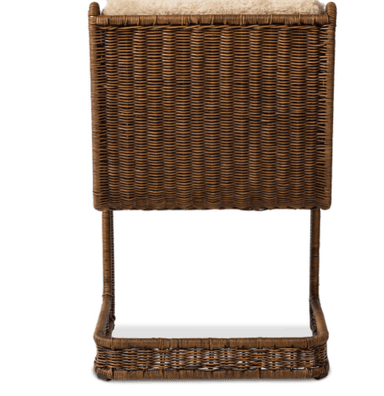 A chair with a rattan or wicker frame and upholstered seat and backrest with a sheepskin or faux sheepskin material. The frame has a woven texture. It features a low shelf or footrest integrated into the base, also constructed from woven material. — 3D model