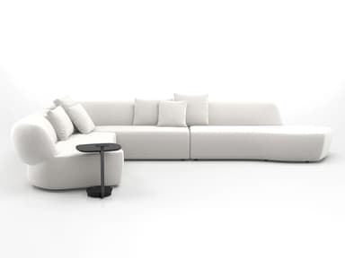 A large, light-colored modular sectional sofa composed of multiple interconnected units. It features a distinctive curved armrest section, several straight seating modules with integrated backrests, and a extended chaise lounge-style end unit. The sofa is upholstered in a textured, light-toned fabric and includes several loose throw pillows for added comfort. A small, black C-shaped side table with a round base is positioned next to the curved armrest section. — 3D model