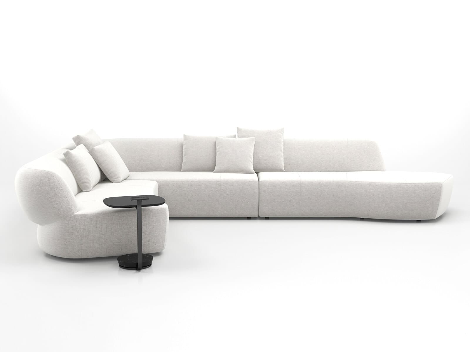 A large, light-colored modular sectional sofa composed of multiple interconnected units. It features a distinctive curved armrest section, several straight seating modules with integrated backrests, and a extended chaise lounge-style end unit. The sofa is upholstered in a textured, light-toned fabric and includes several loose throw pillows for added comfort. A small, black C-shaped side table with a round base is positioned next to the curved armrest section. — 3D model