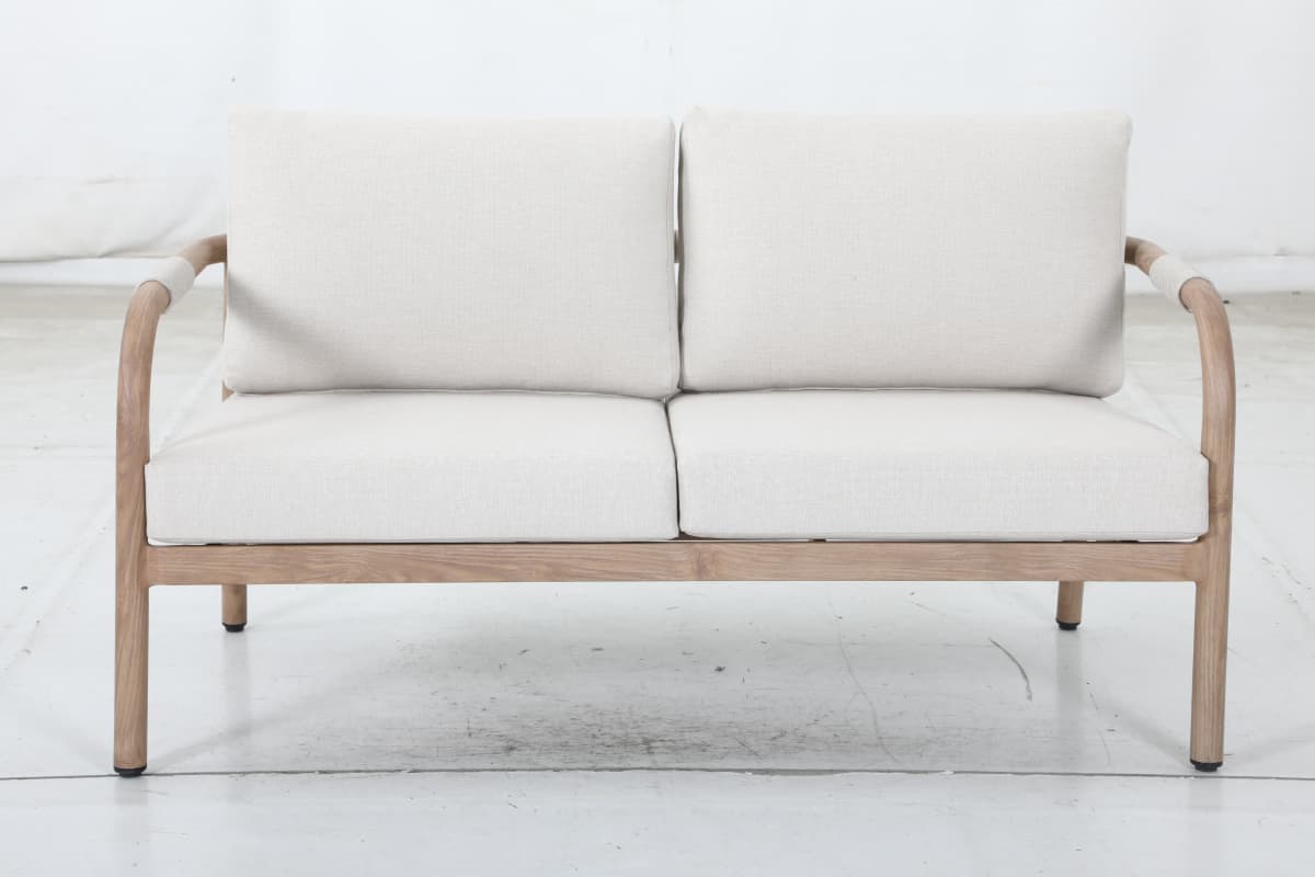 A two-seater sofa with a light-colored wooden frame and light-colored fabric upholstery. The frame features curved armrests and a simple rectangular base. The seat and back cushions are separate and appear to be filled with a soft material. — 3D model