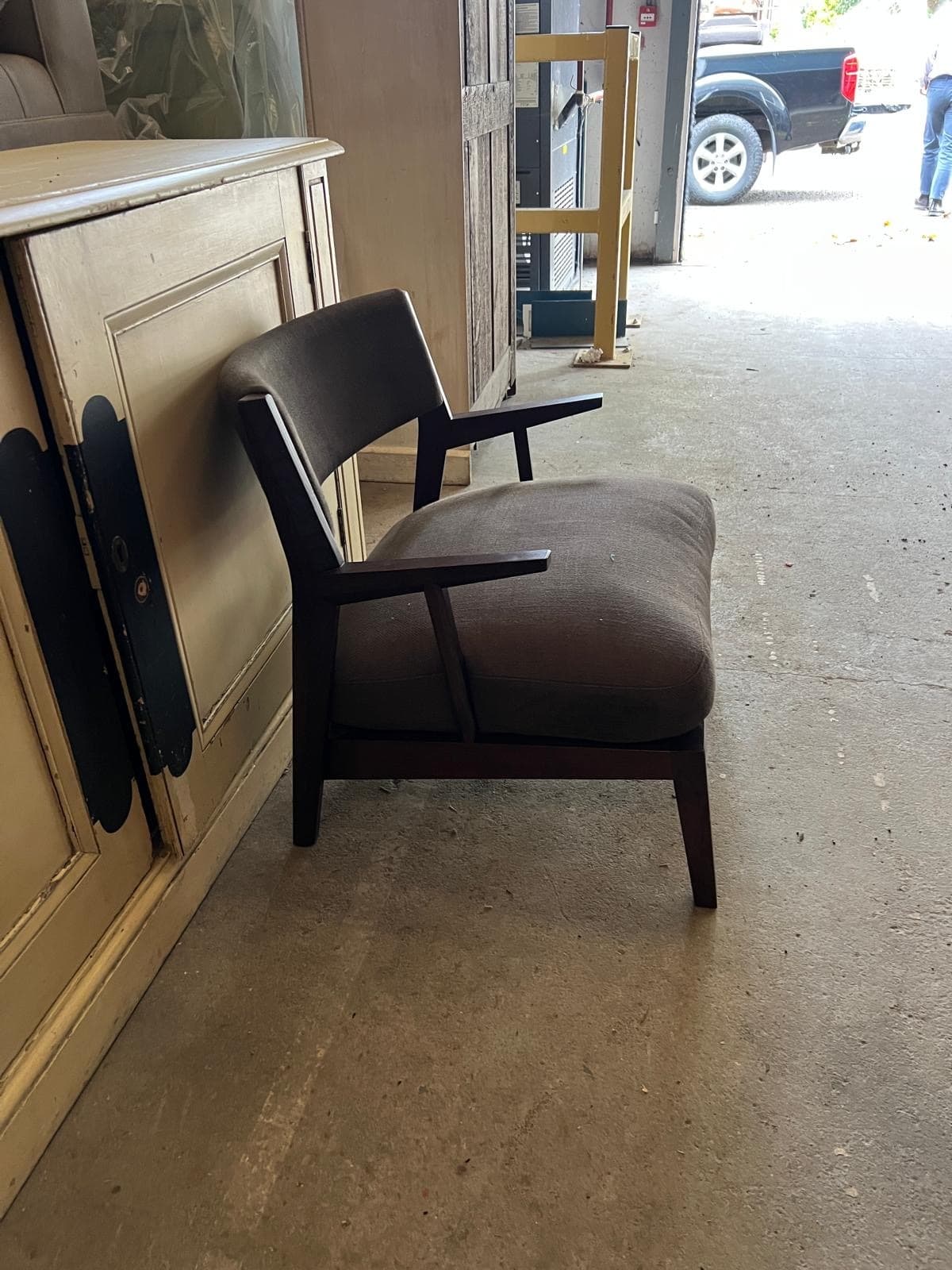 A modern lounge armchair featuring a dark wooden frame and upholstered seat and back in a brown textured fabric. The chair has open armrests and a gently curved backrest. — 3D model