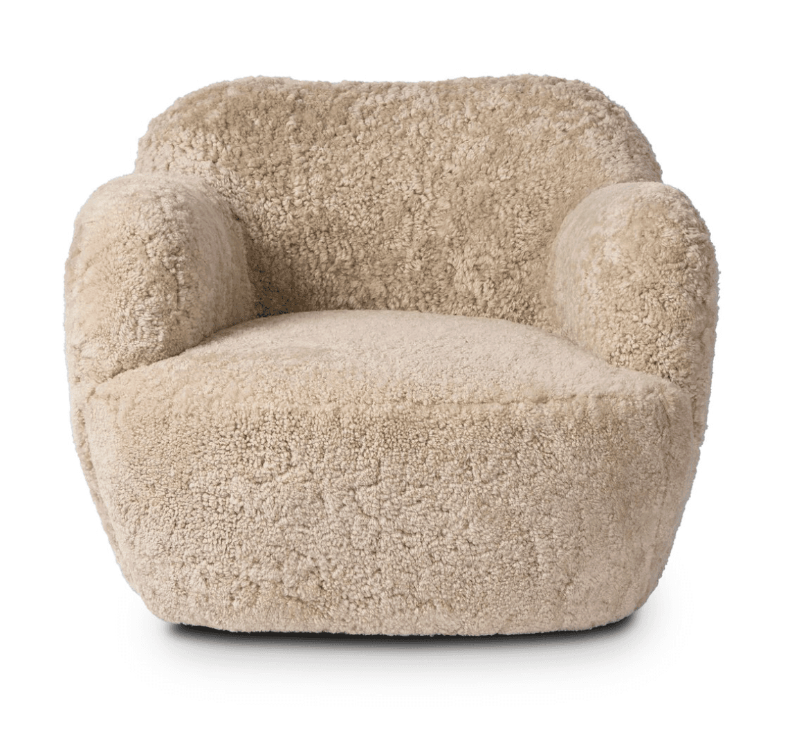 A plush armchair upholstered in a textured, curly, light beige material resembling sheepskin. The chair features a rounded silhouette with integrated armrests that flow into the backrest, and a deep, comfortable seat. The base is solid and integrated with the main body of the chair, lacking distinct legs. The overall design is compact and inviting. — 3D model