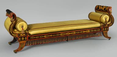 A sophisticated Neoclassical style daybed featuring a long, rectangular cushioned surface upholstered in yellow fabric, flanked by elegant scrolled ends. The wooden frame is lacquered black with intricate gilded and red painted classical motifs, including stylized wings and foliage. Decorative tassels in red and gold adorn the side frame, enhancing its luxurious and historical aesthetic. The daybed stands on short, curved legs. — 3D model
