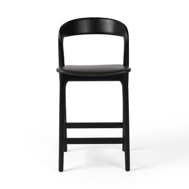 A contemporary bar stool with a black wooden frame and a dark upholstered seat. The stool features a gently curved backrest and a square footrest connecting the tapered legs. — 3D model