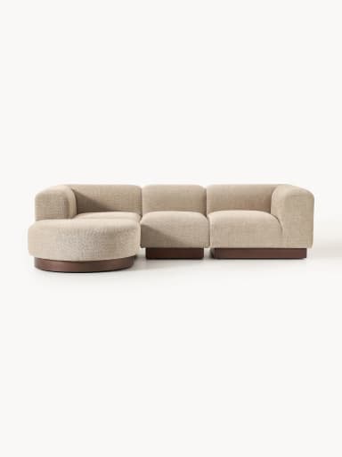 A sectional sofa composed of three distinct modules, including a curved corner piece, an armless central piece, and an end piece with an armrest. The sofa features a textured, boucle-like fabric upholstery and a dark wooden plinth base. — 3D model