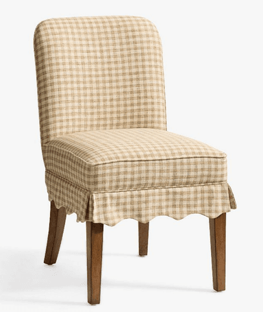 A fully upholstered dining chair featuring a beige and white gingham check pattern. The chair has a tall, slightly curved backrest and a padded seat. A decorative scalloped skirt covers the lower part of the seat frame, partially concealing the upper portion of the four tapered wooden legs. The design suggests a blend of traditional and country-style aesthetics. — 3D model