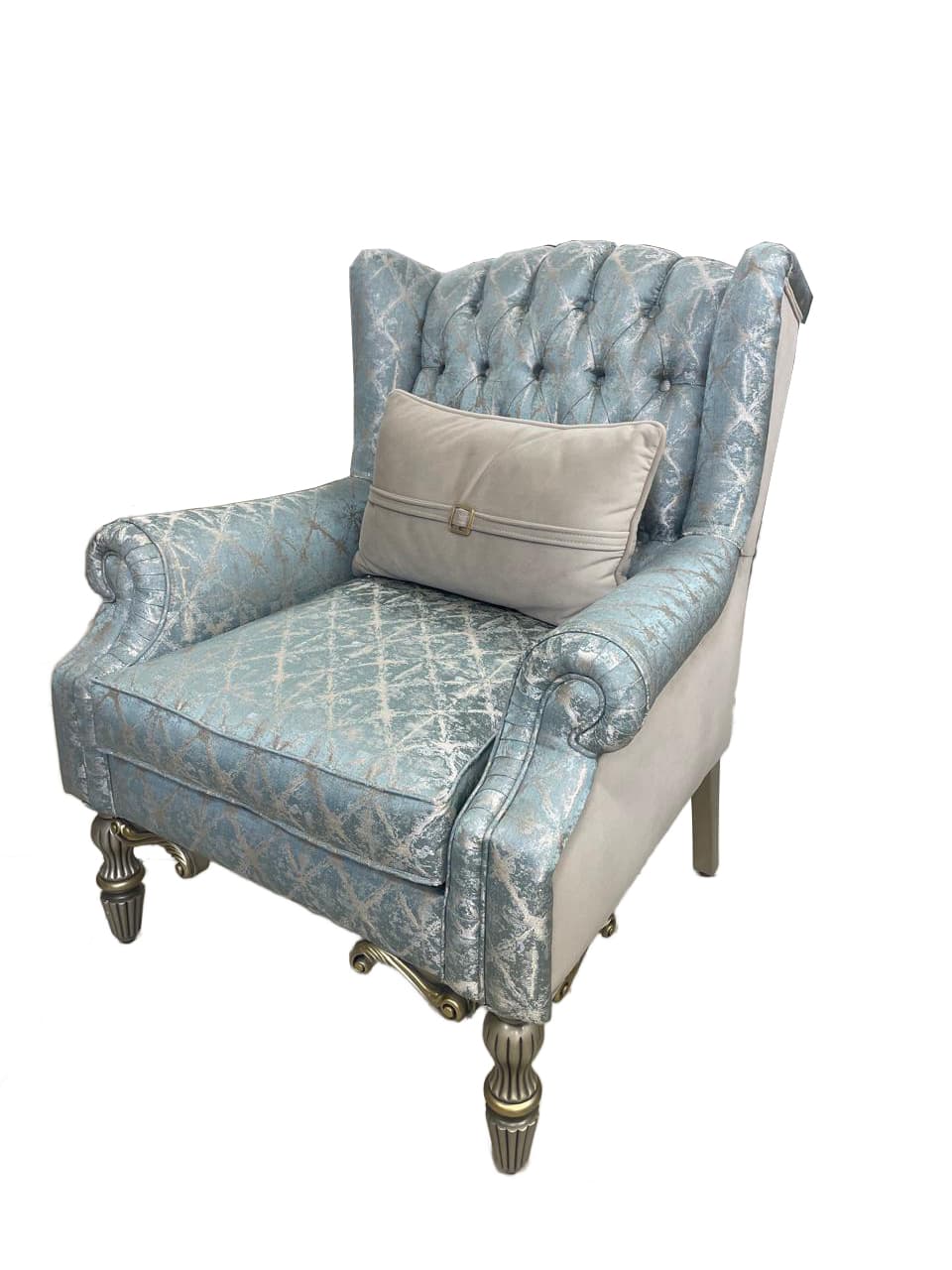 A tufted armchair with a high back and rolled arms, upholstered in a light blue fabric with a silver brocade pattern. The chair features decorative silver trim along the edges and has four turned legs with ornate detailing. A lumbar pillow with a buckle detail is placed on the seat. — 3D model