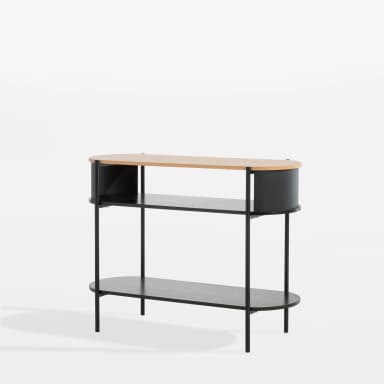 A close-up view of a modern two-tier side table, featuring a light-colored wood tabletop with rounded edges. Below the top, a curved black panel suggests integrated storage or a design enclosure. The table is supported by black vertical cylindrical legs, which also connect to a lower, dark wood-grain shelf, emphasizing a minimalist and contemporary aesthetic. — 3D model