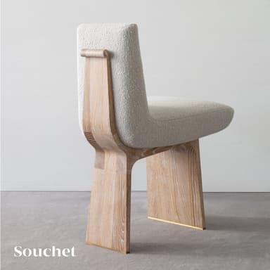 A contemporary armless chair featuring a light-colored boucle upholstered seat and backrest, supported by a distinctive light wood panel base. The wood base has a modern, minimalist design, with the front and back legs being solid, thick panels. The bottom of the wood panels is accented with a metallic brass-toned cap. — 3D model