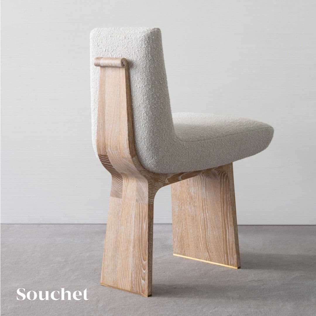 A contemporary armless chair featuring a light-colored boucle upholstered seat and backrest, supported by a distinctive light wood panel base. The wood base has a modern, minimalist design, with the front and back legs being solid, thick panels. The bottom of the wood panels is accented with a metallic brass-toned cap. — 3D model