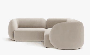 A modular, light beige sectional sofa with rounded edges and a soft, upholstered finish. It features a corner configuration with two distinct modules, one appearing to be a corner seat and the other an armless or low-arm section. The design is minimalist and contemporary, with a focus on plush comfort and organic shapes. The sofa is presented against a plain white background. — 3D model