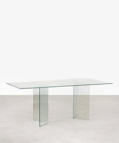 A rectangular table constructed entirely from clear glass, featuring a flat top supported by two distinct angled glass panel bases. — 3D model
