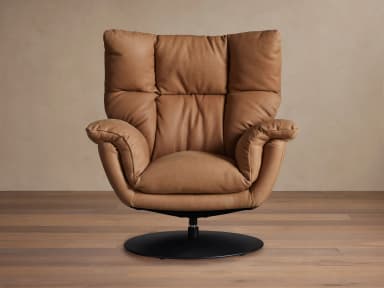 A contemporary armchair upholstered in tan leather, featuring a plush, segmented backrest and seat, rounded armrests, and a circular swivel base in black metal. The design emphasizes comfort with its soft, yielding upholstery and supportive structure. — 3D model