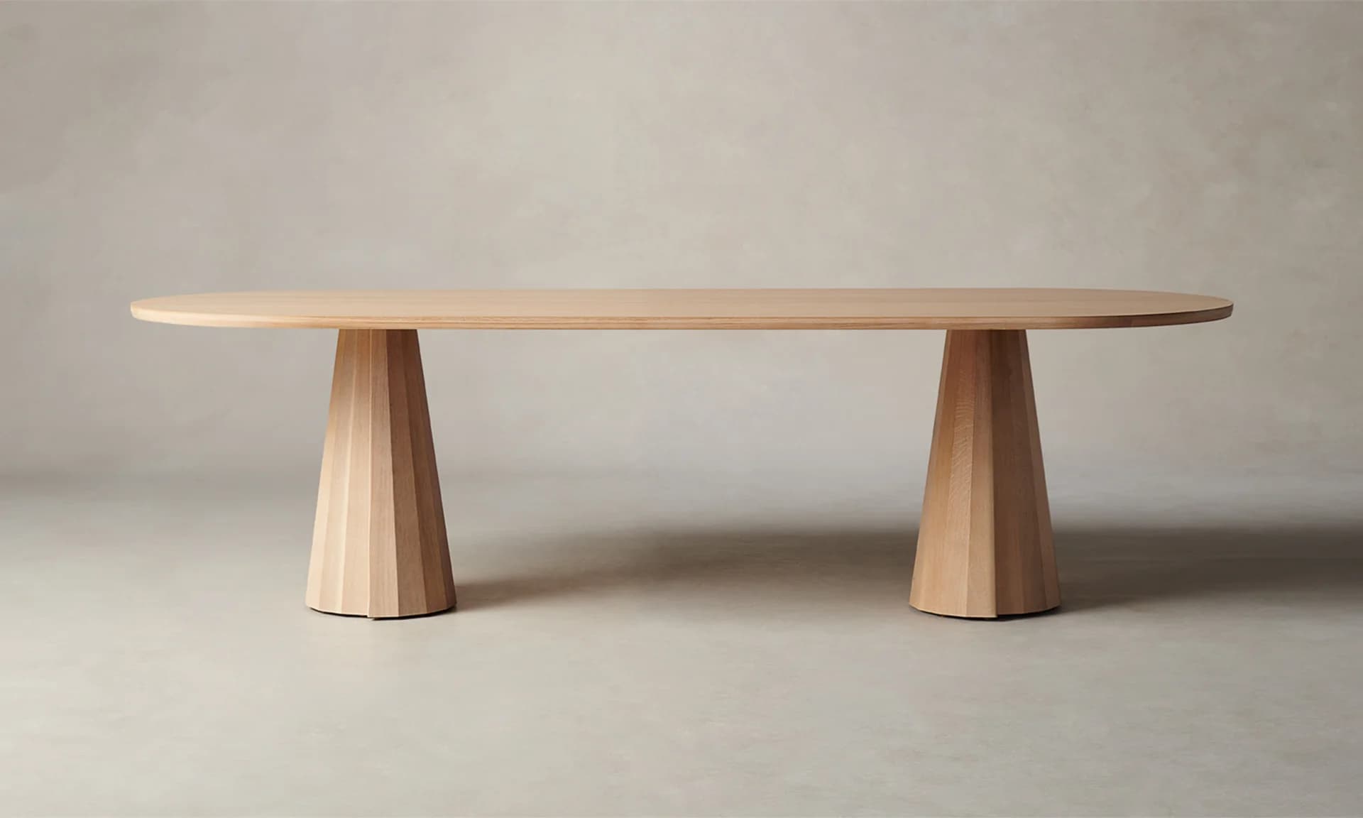An oval-shaped dining table with a light wood finish. The tabletop is relatively thin with rounded edges. It is supported by two conical bases, each featuring a fluted or segmented design, tapering from a wider base to a narrower top where they connect to the underside of the tabletop. The bases appear to be made of solid wood. — 3D model