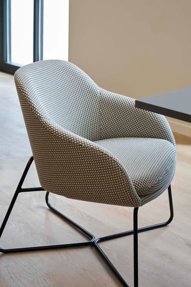 A modern upholstered lounge armchair featuring a curved gray fabric shell with integrated arms and a separate seat cushion, supported by a minimalist black metal sled base. — 3D model