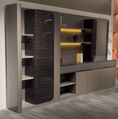 A modern wall-mounted entertainment center featuring a multi-component design with open shelving, enclosed cabinets, and lower drawer storage. The unit combines a taupe/greige finish with dark, horizontally-grained wood accents on some cabinet faces and rounded elements. It includes display niches, illuminated shelves, and fluted textured panels. — 3D model