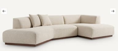 A modular sectional sofa with a low profile and clean lines. The sofa features a textured fabric upholstery and a dark wood base. It is configured with a chaise lounge on the left and a corner section on the right, accompanied by two square throw pillows. — 3D model